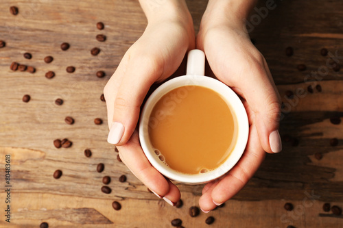 Female hands holding cup with coffee beans