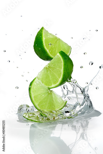 Three slices of lime falling into water