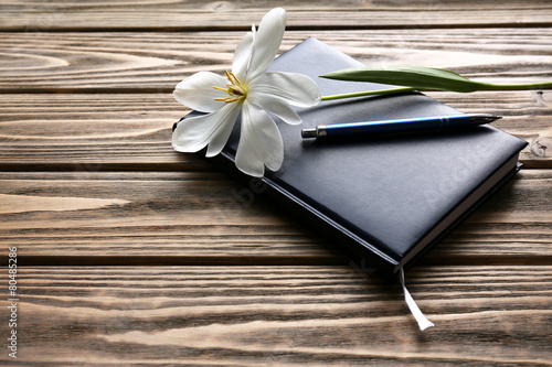 Fototapeta Naklejka Na Ścianę i Meble -  Notebook with pen and white tulip on wooden background