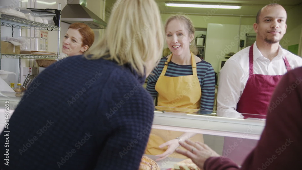 Friendly staff serving customers with a smile at the bakery counter Friendly staff serving customers with a smile at the bakery counter
