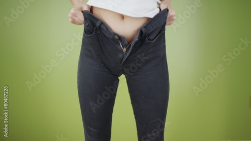 Time to go on a diet - woman struggling to get into too tight jeans
