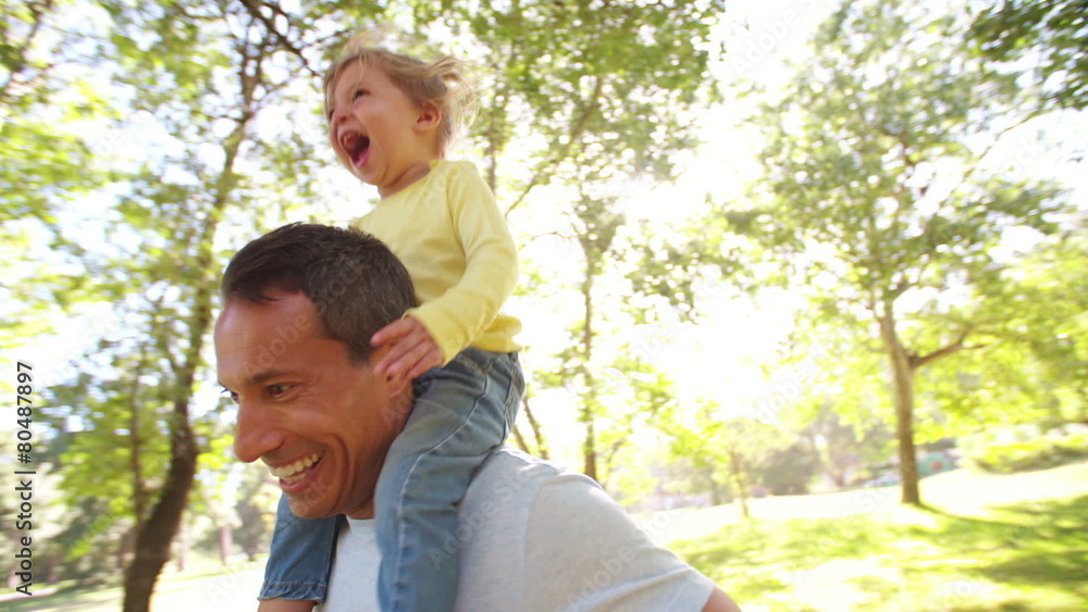 Smiling dad carrying his happy little girl on his shoulders Smiling dad carrying his happy little girl on his shoulders
