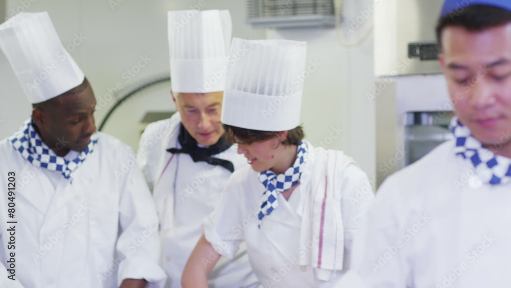 Head chef in commercial kitchen overseeing staff and offering advice Head chef in commercial kitchen overseeing staff and offering advice