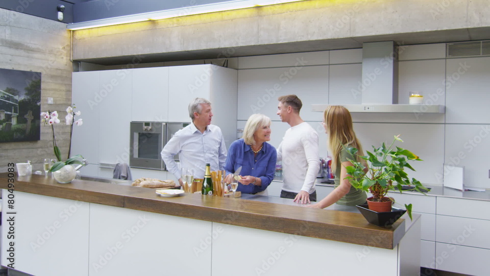 Happy adult family group greeting each other in the kitchen of the family home Happy adult family group greeting each other in the kitchen of the family home