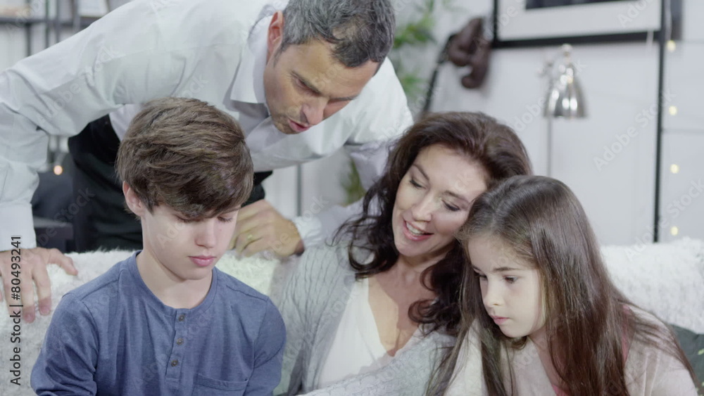 Young boy reads aloud to his parents and his sister at home Young boy reads aloud to his parents and his sister at home
