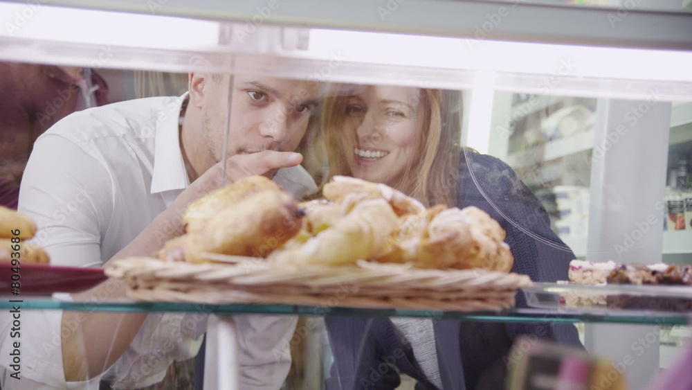 Happy attractive young couple choosing fresh pastries at the bakery counter Happy attractive young couple choosing fresh pastries at the bakery counter