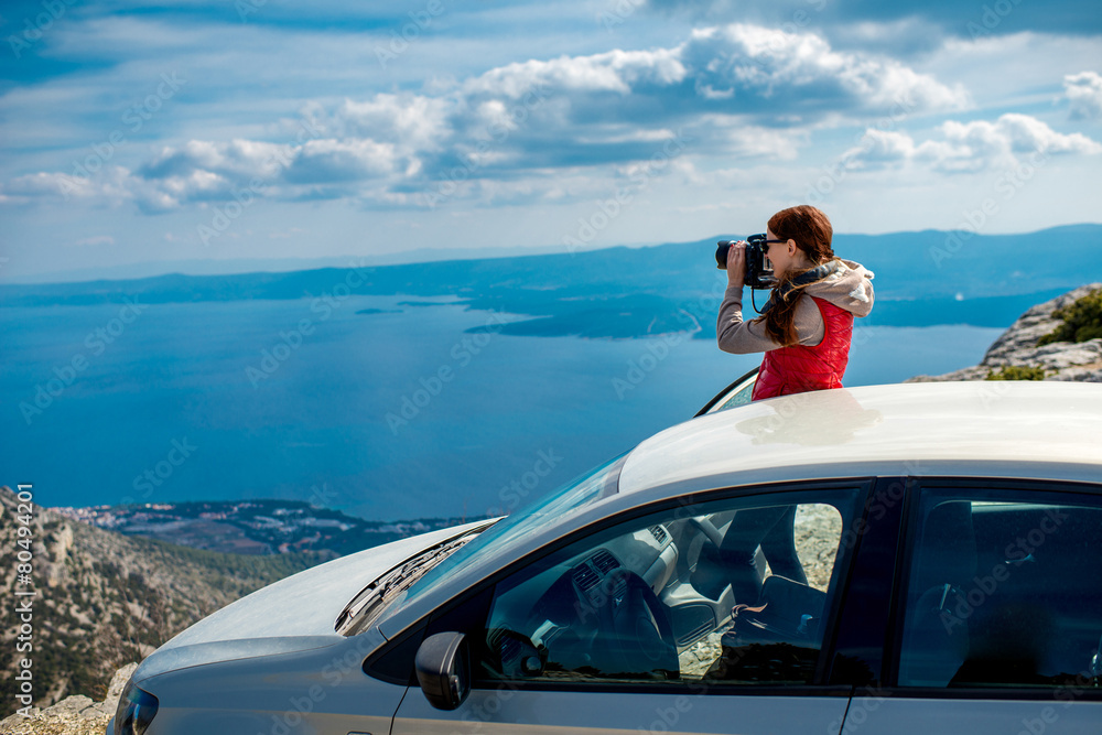 Woman photographer with car on the top of mountain