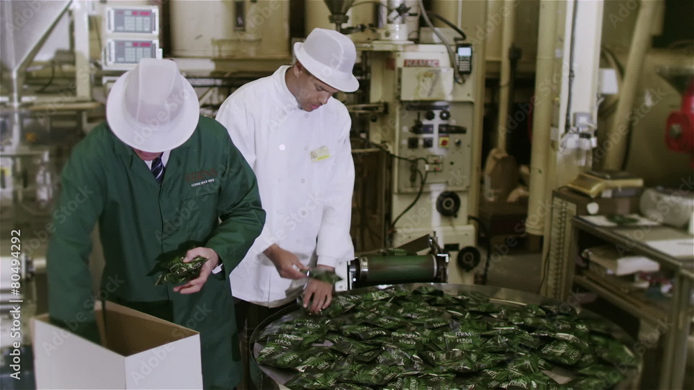 Workers in a beverage factory sorting and packing packets of fresh coffee Workers in a beverage factory sorting and packing packets of fresh coffee