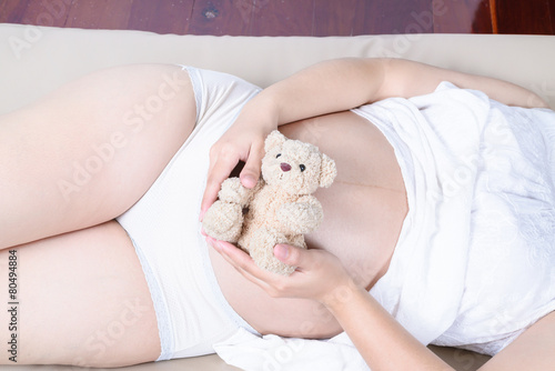pregnant woman with hands and have bear doll
