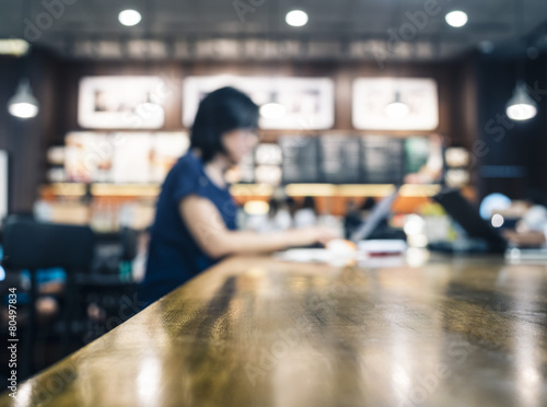 Woman working with laptop on table in blurred cafe background