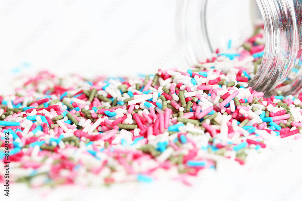 Spilled sprinkles with container on white background Spilled sprinkles with container on white background