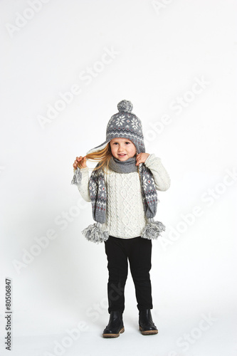 Beautiful blond girl playing in the winter warm hat and scarf on