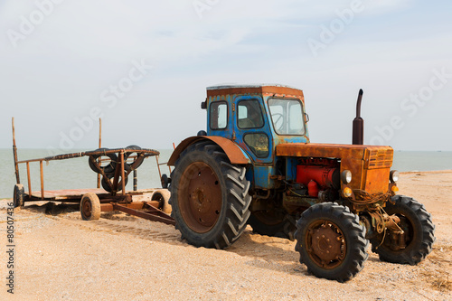 old orange tractor on the sandy beach. Azov sea. dolganka