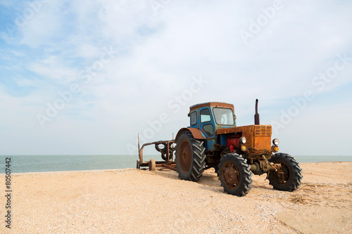 old orange tractor on the sandy beach. Azov sea. dolganka