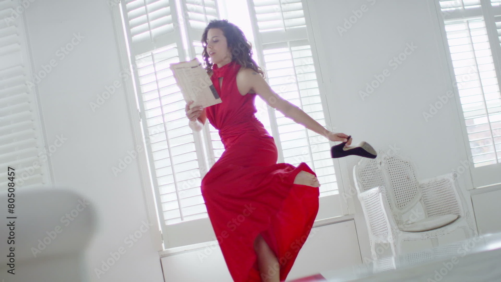 Beautiful woman in evening gown returns home and takes off her shoes Beautiful woman in evening gown returns home and takes off her shoes