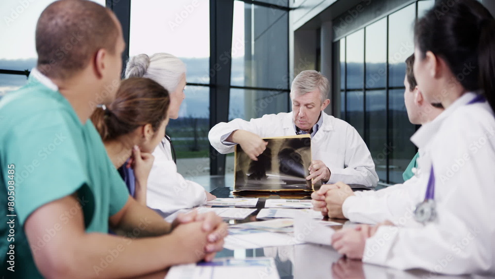 Multi ethnic medical team in a meeting discuss a patient's x-ray results Multi ethnic medical team in a meeting discuss a patient's x-ray results