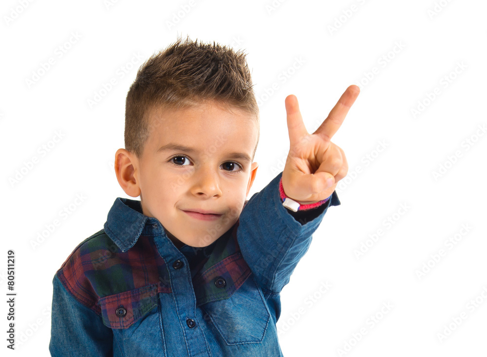 Kid doing victory gesture over white background Kid doing victory gesture over white background