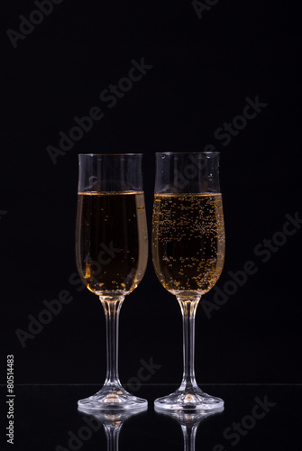 two glasses of champagne over black background