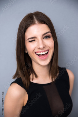 Happy woman winking over gray background