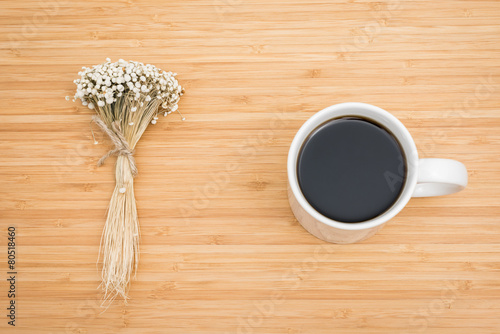 a cup of coffee and dry flower on the wooden background.