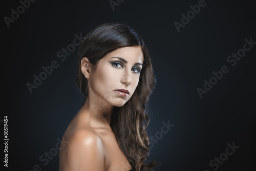 Beauty portrait of attractive brunette woman against dark blue b