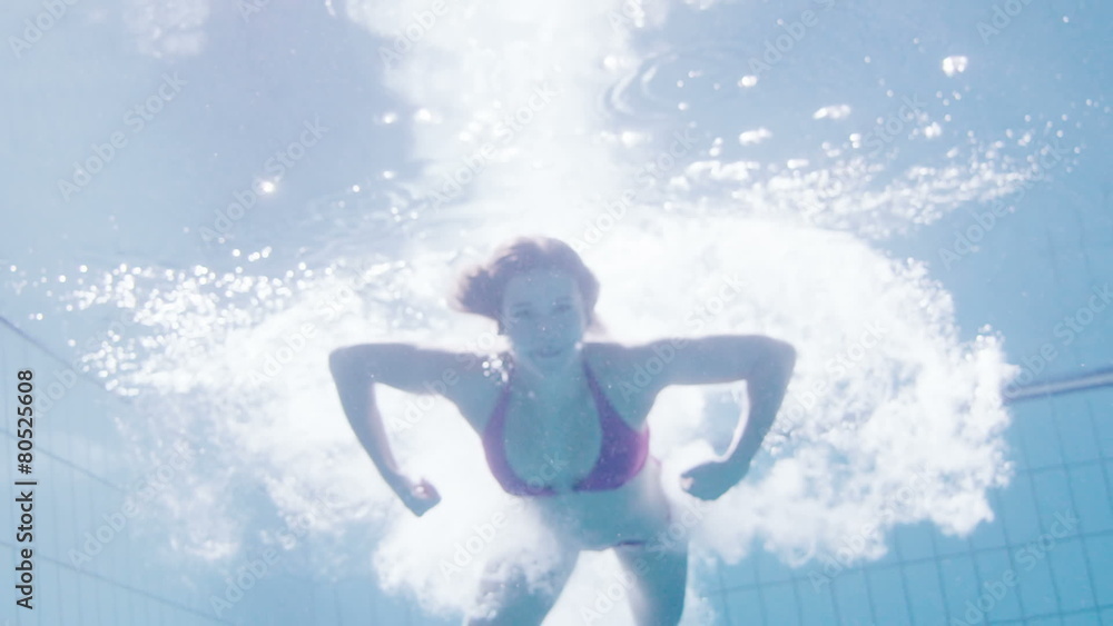 Beautiful woman in a pink bikini diving in and swimming underwater Beautiful woman in a pink bikini diving in and swimming underwater