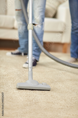 close up of human legs and vacuum cleaner at home