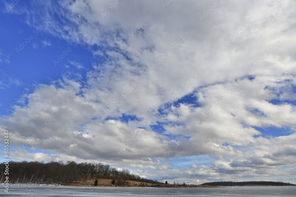 Storm clouds landscape over frozen lake.