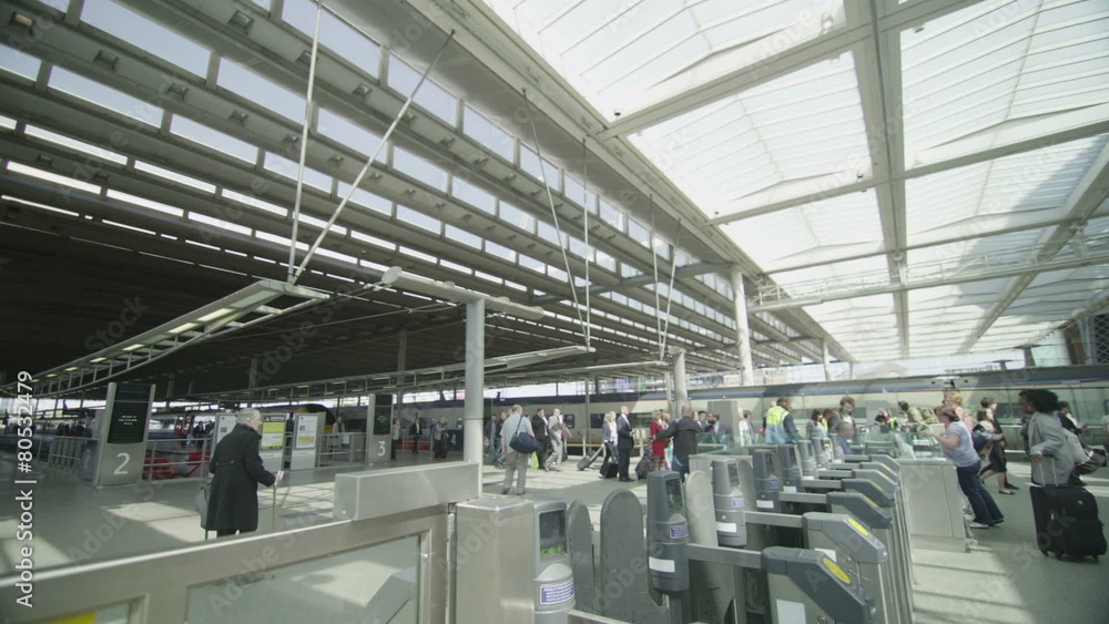 Travelers & commuters passing through ticket barrier at a London railway station Travelers & commuters passing through ticket barrier at a London railway station