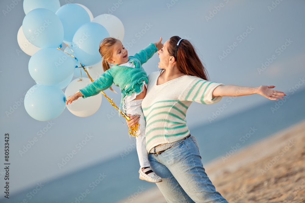 Mother with her daughter play with balloons by the sea Mother with her daughter play with balloons by the sea