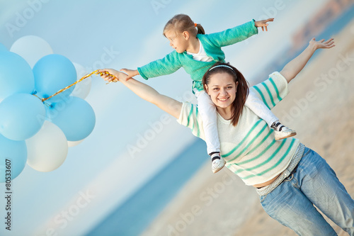 Mother with her daughter play with balloons by the sea