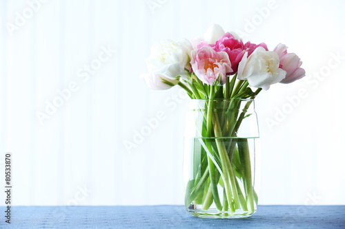 Fototapeta Naklejka Na Ścianę i Meble -  Beautiful tulips in glass vase on light background