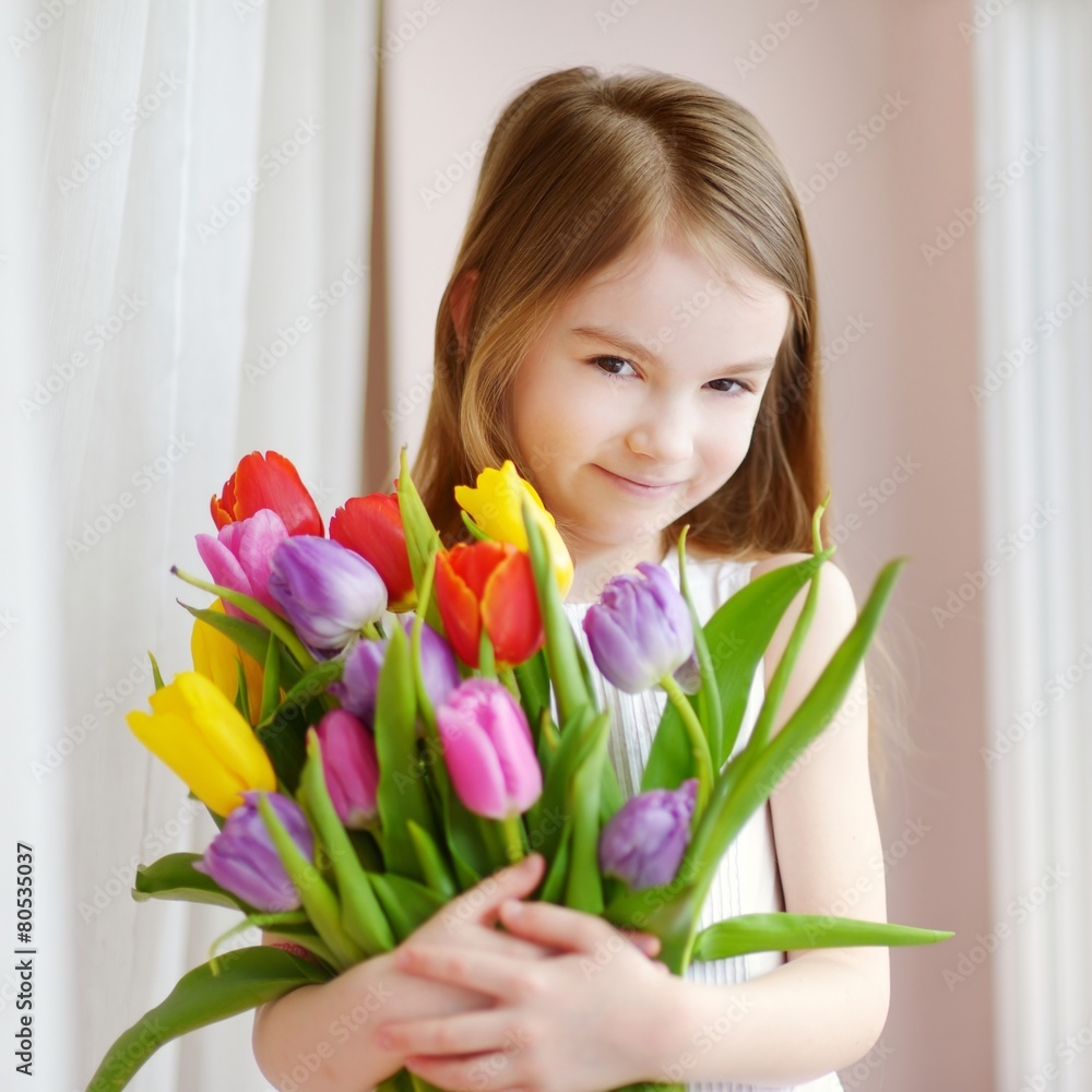 Adorable little girl holding tulips by the window Adorable little girl holding tulips by the window