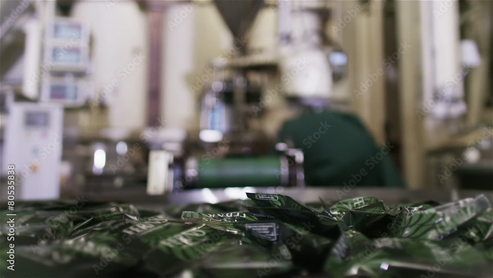Packets of fresh coffee moving along factory conveyor belt ready for packing Packets of fresh coffee moving along factory conveyor belt ready for packing