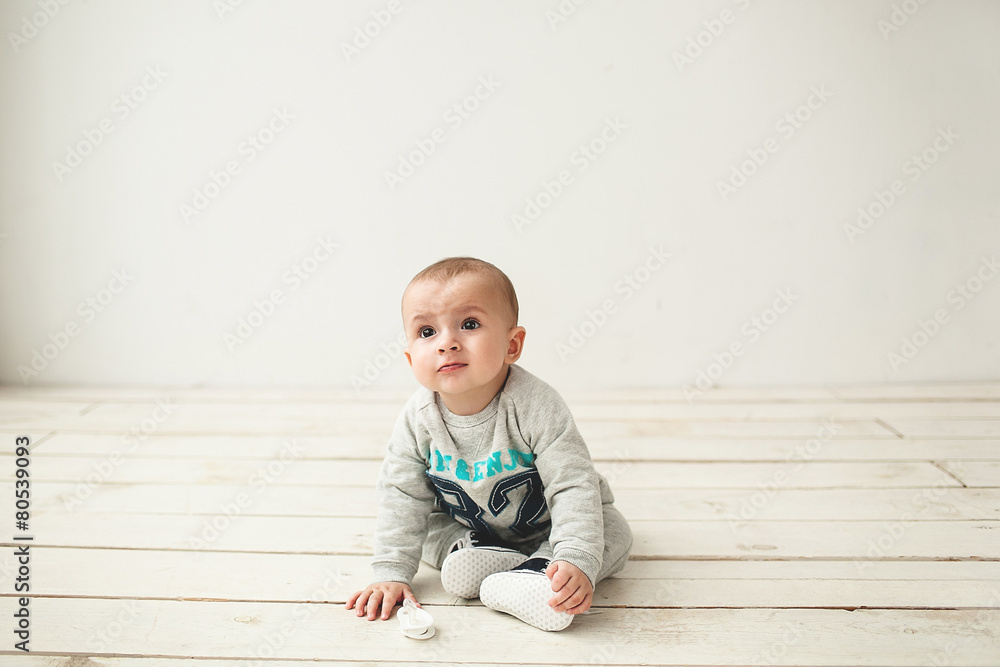 Naklejka premium One year old cute baby boy sitting on wooden floor