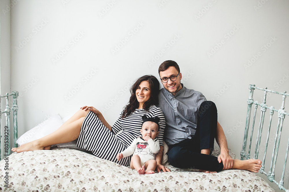 Happy young father, mother and cute baby boy lying on rustic bed Happy young father, mother and cute baby boy lying on rustic bed