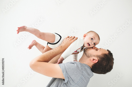 Happy father holding baby in hands over head isolated background