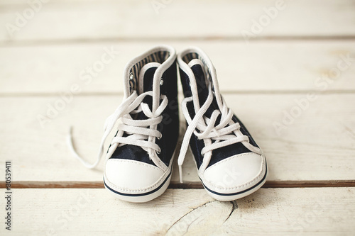 Baby black and white sneakers on wooden floor
