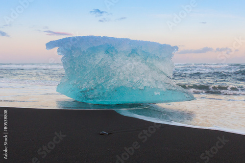 Ice cube on black volcano sand beach, Iceland photo