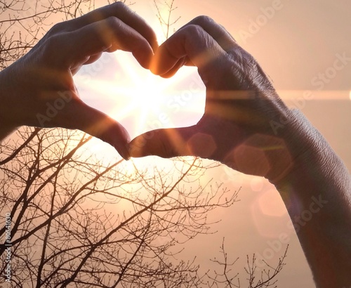 Menschenhände zeigen die Sonne im Herzen