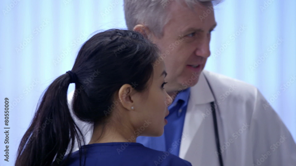 Doctor and nurse on a hospital ward having a discussion about a patient Doctor and nurse on a hospital ward having a discussion about a patient
