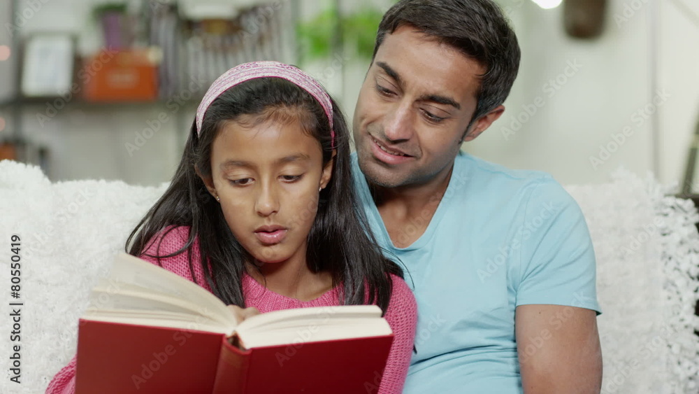 A father and his daughter spending time together at home, reading a book A father and his daughter spending time together at home, reading a book