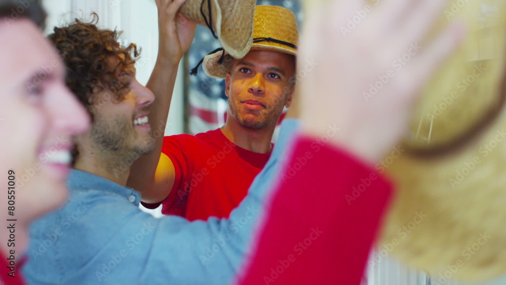 Young happy group of friends have fun trying on a selection of straw hats Young happy group of friends have fun trying on a selection of straw hats