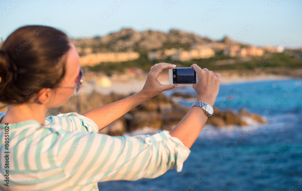 Fototapeta premium Young woman take a picture on phone during beach vacation