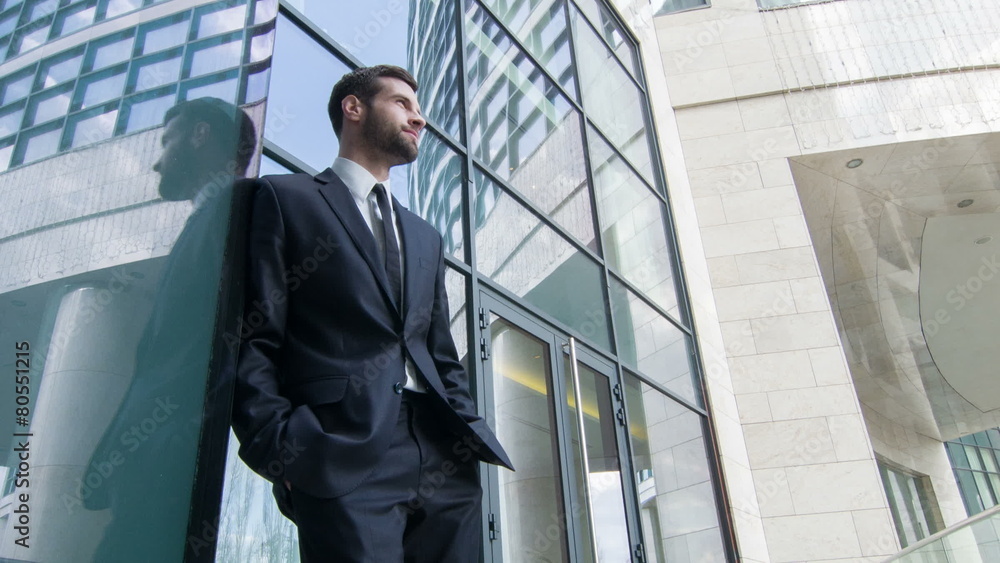 Low angle view of businessman standing by the skyscraper Low angle view of businessman standing by the skyscraper