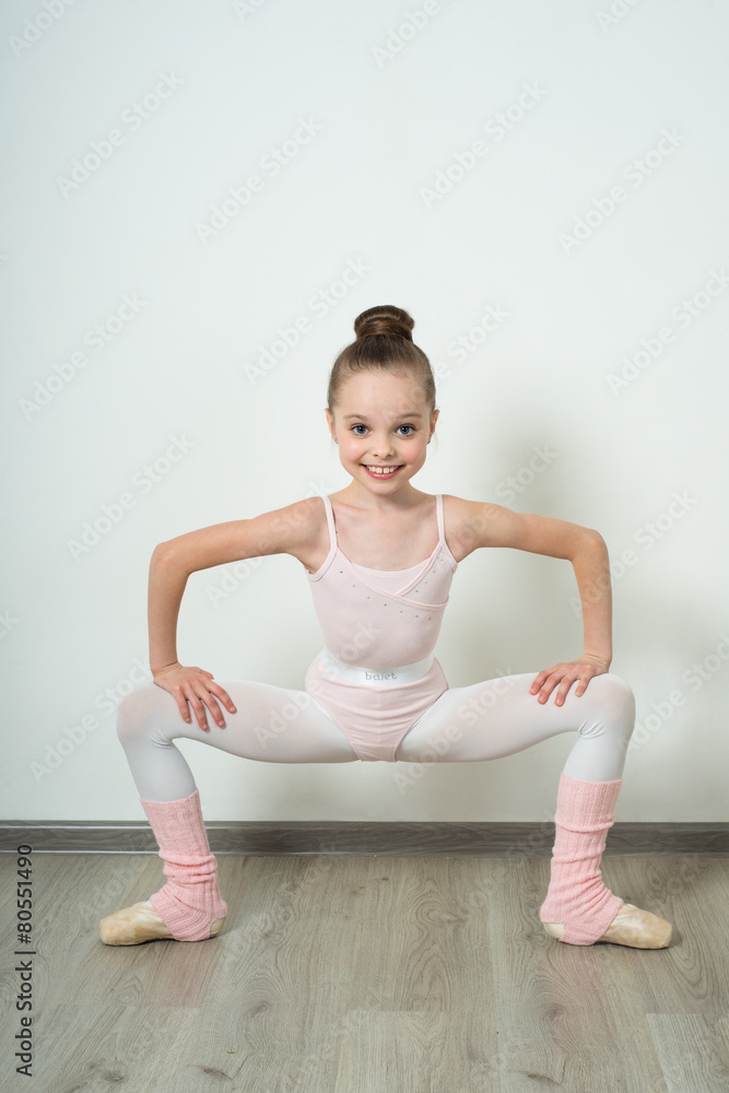 Obraz premium A little adorable young ballerina posing and stretching