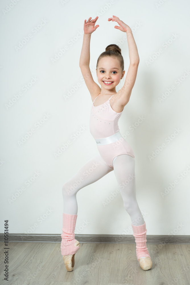 Fototapeta premium A little adorable young ballerina posing and stretching