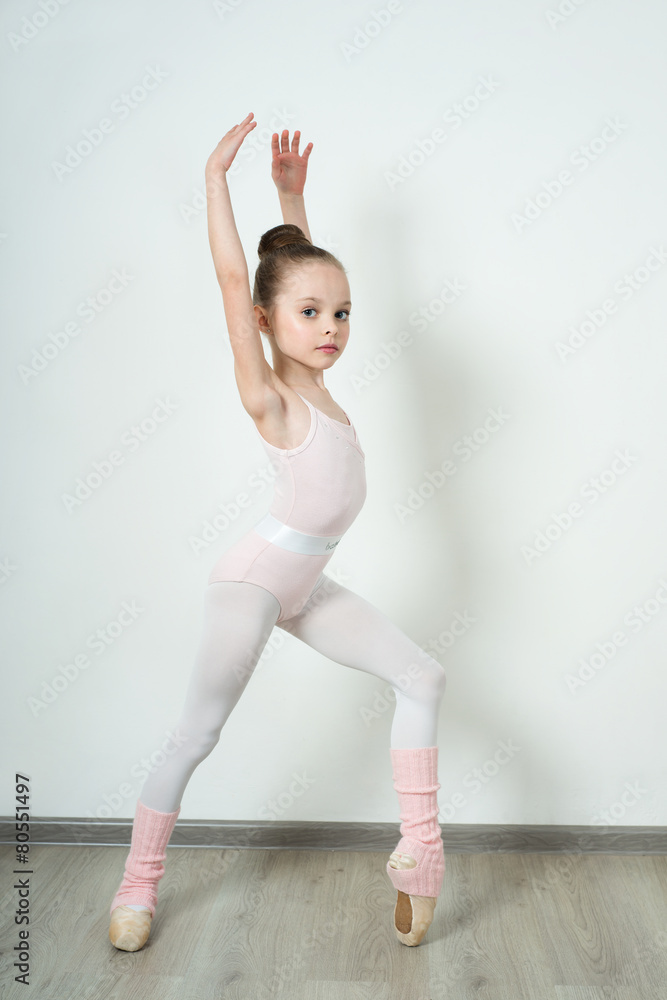 Obraz premium A little adorable young ballerina posing and stretching