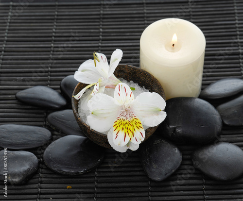 White orchid with salt in bowl and black stones on mat