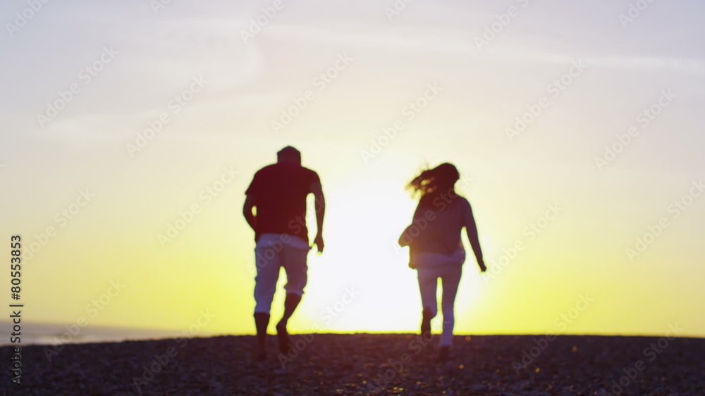 Romantic couple running on the beach at sunset Romantic couple running on the beach at sunset